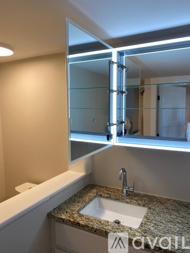 A bathroom with a sink, mirror, and lighting fixture.