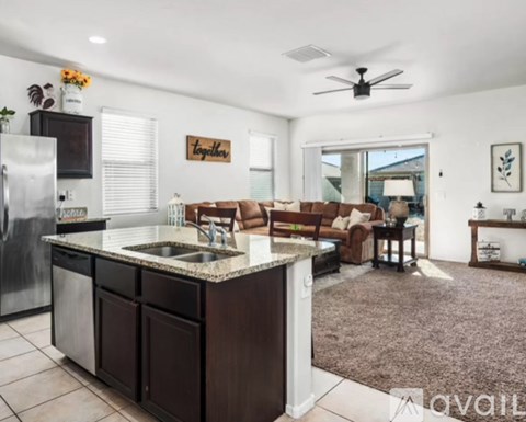 A kitchen with a refrigerator, sink, and a dining table with chairs.