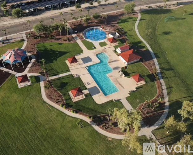 An aerial view of a pool surrounded by a grassy area and a few buildings.