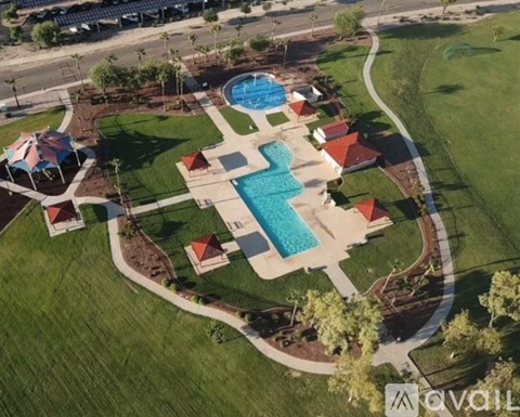 An aerial view of a pool surrounded by a grassy area and a few buildings.