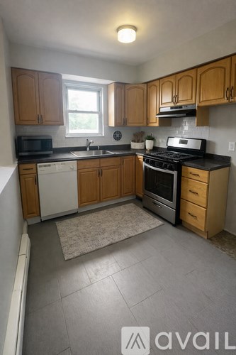 A kitchen with wooden cabinets and a rug on the floor.