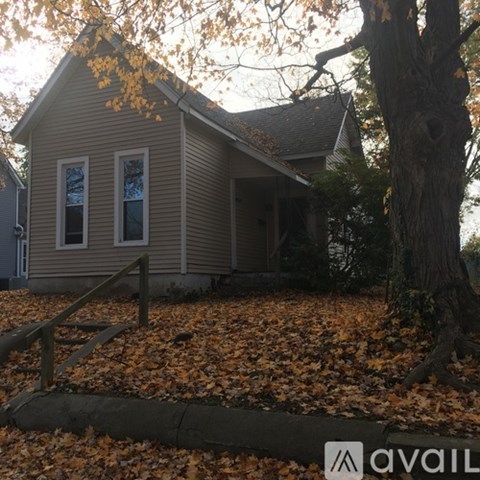 A house with a porch and a tree in front.