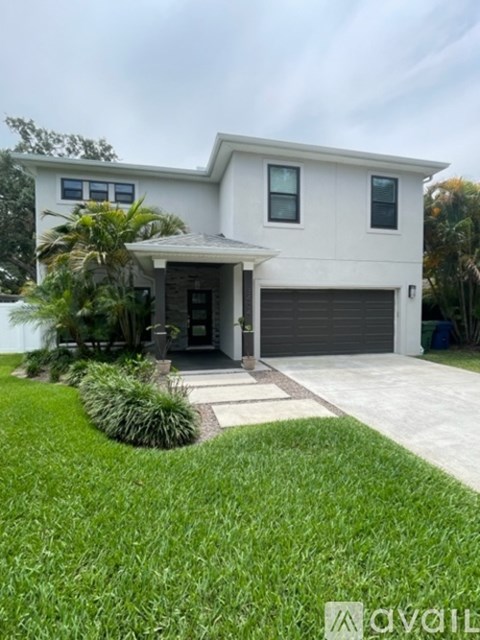 A white house with a black garage door and a small front yard.