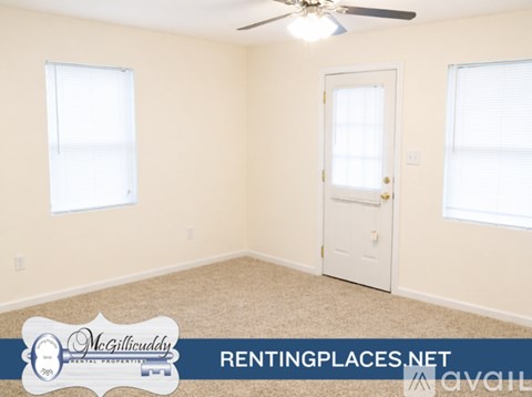 A room with a carpeted floor, a ceiling fan, and two windows.