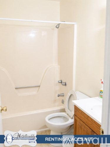 A white toilet in a bathroom with a white tub.