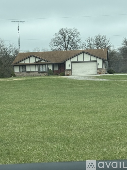 A house with a garage is situated in a grassy area.