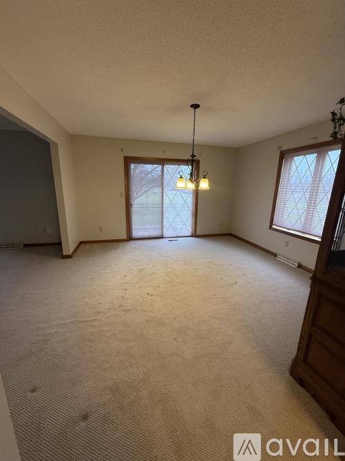 A room with a carpeted floor and a window with blinds.