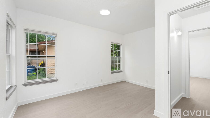 A room with a window showing a view of a building and trees outside.