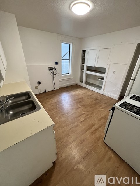 A kitchen with a sink, stove, and wooden floors.