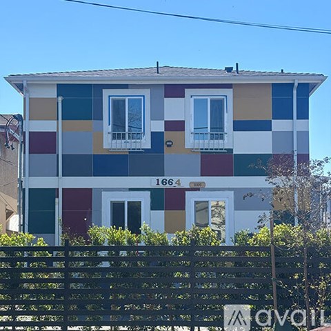 A two-story house with a black fence in front.