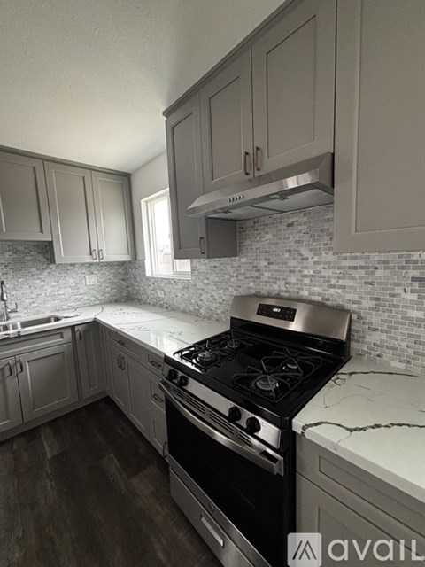 A kitchen with a black stove top oven and white cabinets.
