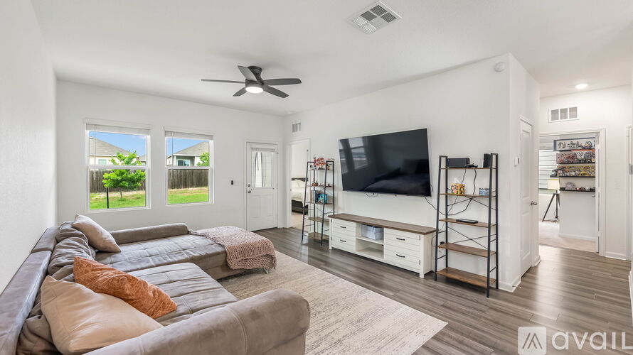 A living room with a couch, television, and a fan.