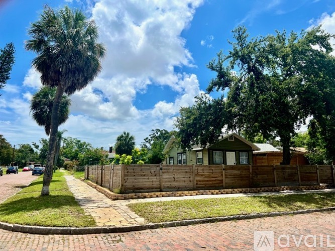 A residential area with a house, trees, and a fence.