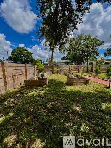 A backyard with a wooden fence and a tree.
