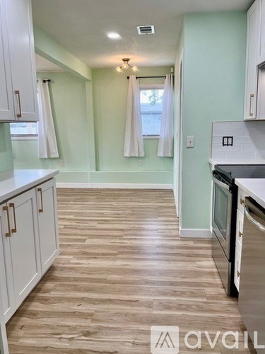 A kitchen with white cabinets and a wooden floor.
