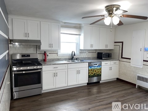 A kitchen with white cabinets and a wood floor.
