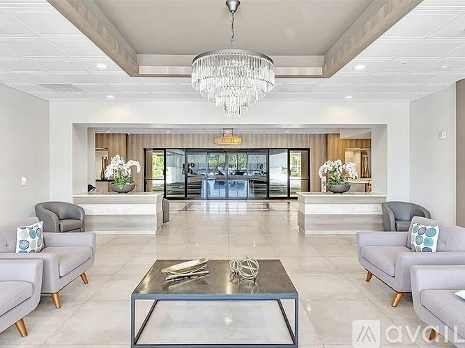A modern living room with a glass coffee table and grey couches.