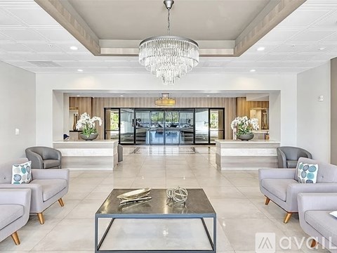 A modern living room with a glass coffee table and grey couches.