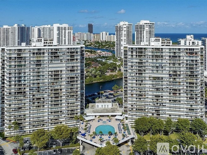 A view of a city with apartment buildings, a pool, and a body of water.