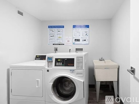 A washing machine and dryer in a small room with instructions on the wall.
