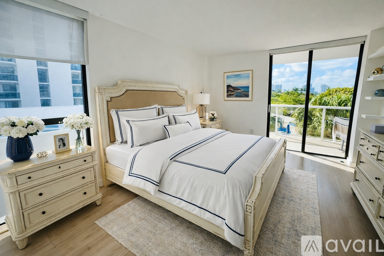 A bedroom with a large bed, a dresser, and a view of the city.