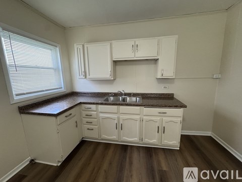 A kitchen with white cabinets and brown countertops.
