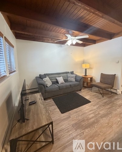 A living room with a grey couch, a black chair, and a wooden floor.