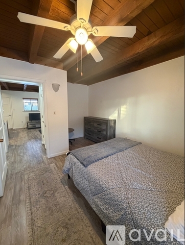 A bedroom with a bed, dresser, and ceiling fan.