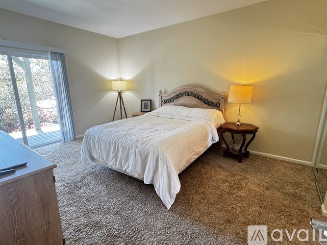 A bedroom with a large bed and two lamps.