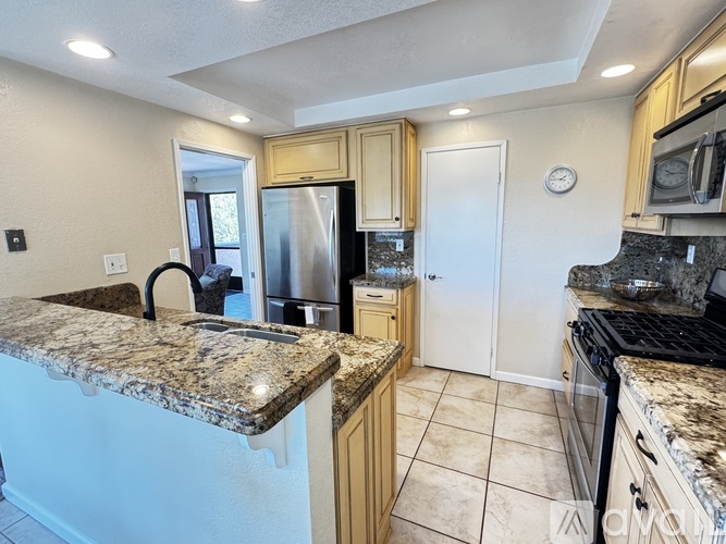 A kitchen with granite countertops and wooden cabinets.