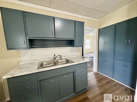 A kitchen with a marble countertop and grey cabinets.