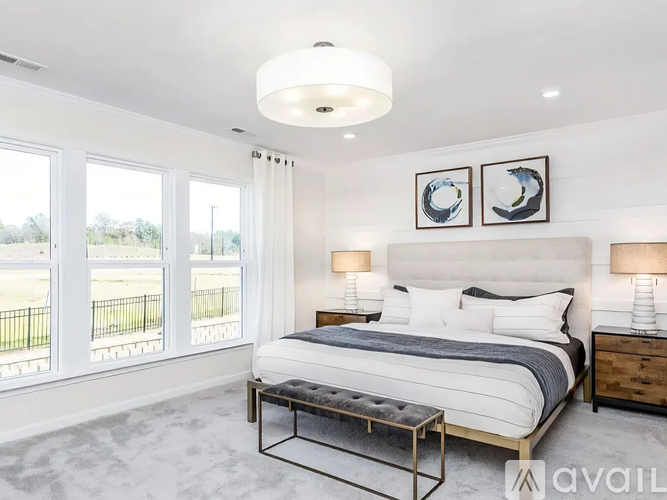 A bedroom with a large bed, two lamps, and two pictures on the wall.
