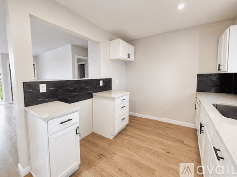 A kitchen with white cabinets and a black countertop.