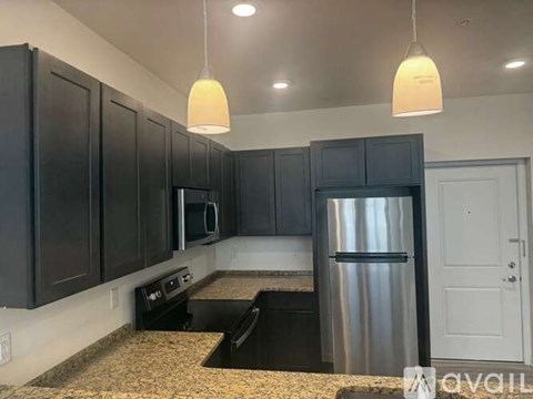 A kitchen with black cabinets and a stainless steel refrigerator.