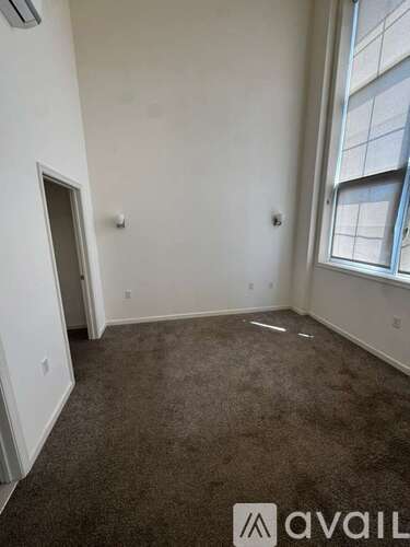 A room with a carpeted floor and a window with a view of a building.