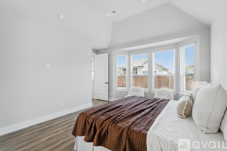 A bedroom with a large bed and a view of the outside through the window.