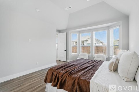 A bedroom with a large bed and a view of the outside through the window.