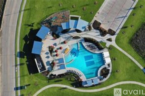 An aerial view of a swimming pool surrounded by a grassy area and a building.