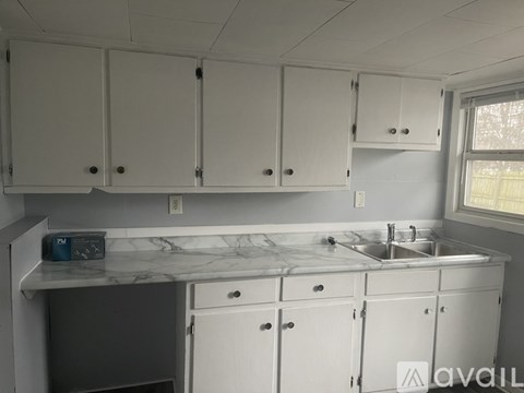 A kitchen with white cabinets and a marble countertop.