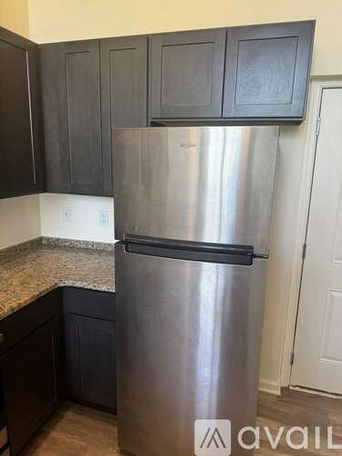 A stainless steel refrigerator in a kitchen with dark wood cabinets.