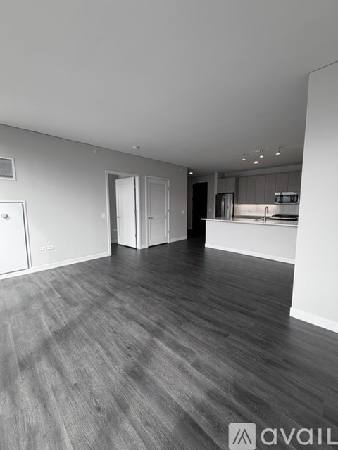 A spacious room with wooden flooring and white walls.