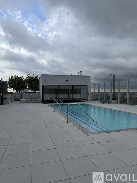 A swimming pool area with a building and a cloudy sky.