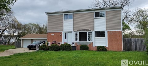 A two-story house with a garage and a car parked in front.