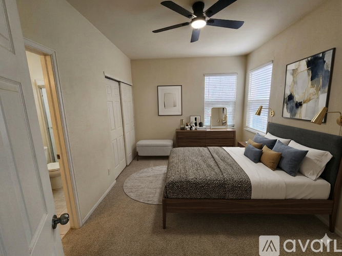 A bedroom with a bed, a bench, and a ceiling fan.