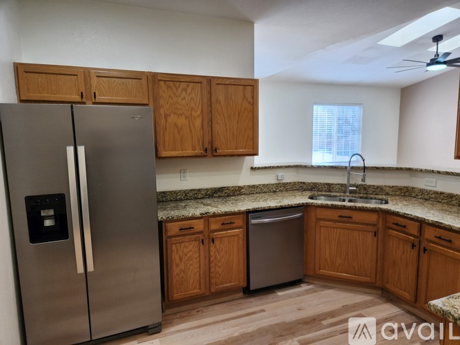 A kitchen with a stainless steel refrigerator and wooden cabinets.
