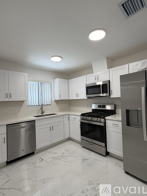A modern kitchen with white cabinets and stainless steel appliances.