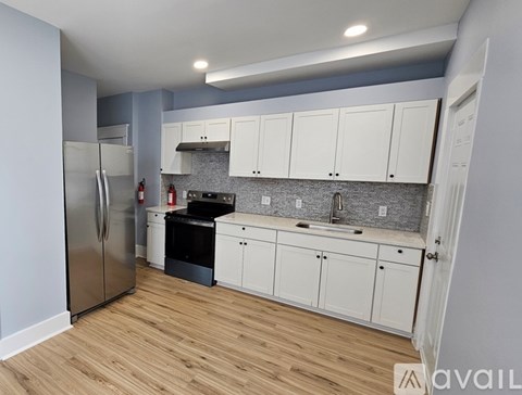 A kitchen with white cabinets and a stainless steel refrigerator.