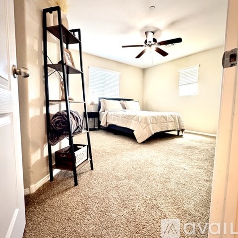 A bedroom with a bed, a ladder, and a ceiling fan.