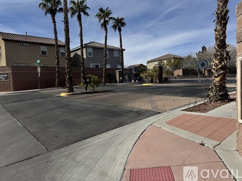 A street view of a residential area with palm trees and houses.