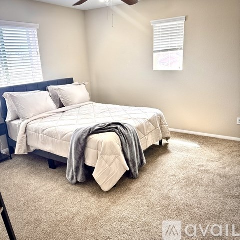 A bedroom with a bed, pillows, and a ceiling fan.
